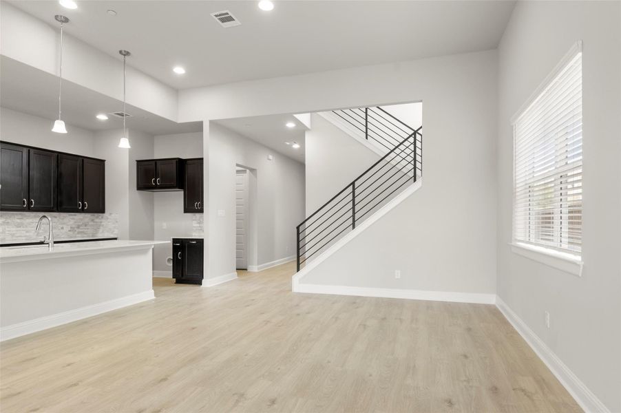 Unfurnished living room with light wood-type flooring, stairs, and recessed lighting Unfurnished living room with light wood-type flooring, stairs, and recessed lighting