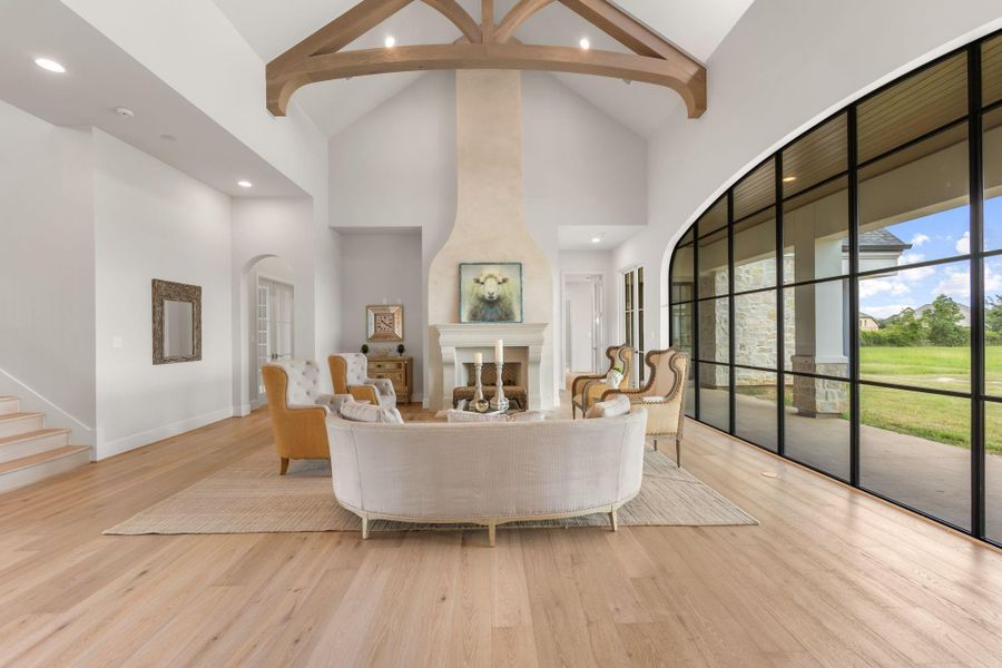 Living room with beautiful cast stone and glazed fireplace. On the left is the hall to the office and library and powder room. On the right is the hall to the primary suite. Living room with beautiful cast stone and glazed fireplace. On the left is the hall to the office and library and powder room. On the right is the hall to the primary suite.