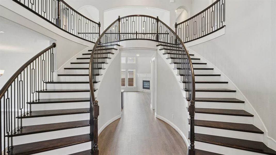 Stairway with a towering ceiling, wood finished floors, and a glass covered fireplace Stairway with a towering ceiling, wood finished floors, and a glass covered fireplace