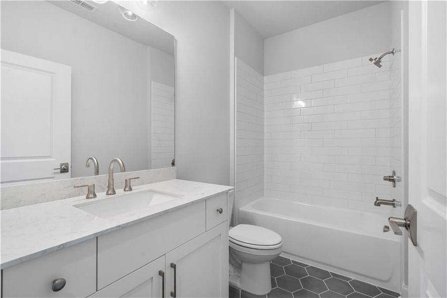 Full bath featuring shower / tub combination, vanity, and dark tile patterned floors Full bath featuring shower / tub combination, vanity, and dark tile patterned floors