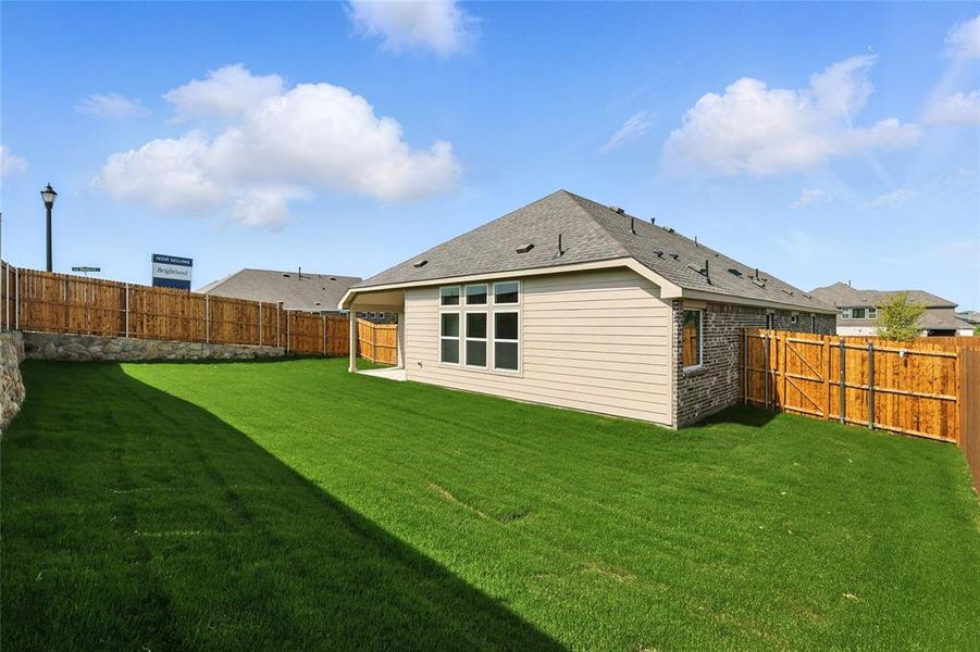 Rear view of house featuring a fenced backyard, brick siding, and a shingled roof