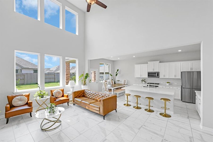 The bright, open-concept living space features high ceilings with large windows & a modern kitchen with a large island. The room is well-lit, airy, and seamlessly connects living and dining areas, ideal for entertaining and comfortable living.