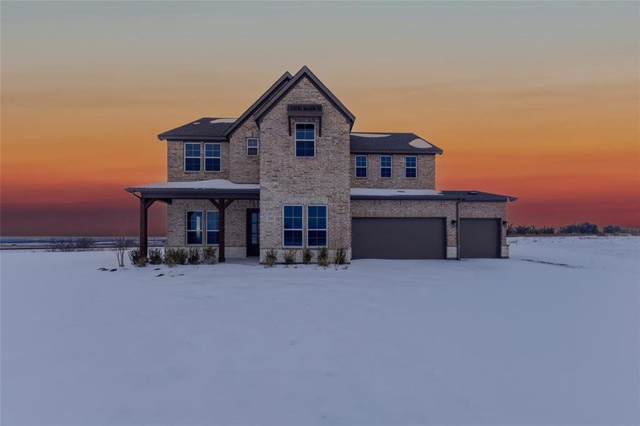 View of front of house featuring brick siding, covered porch, driveway, and an attached garage