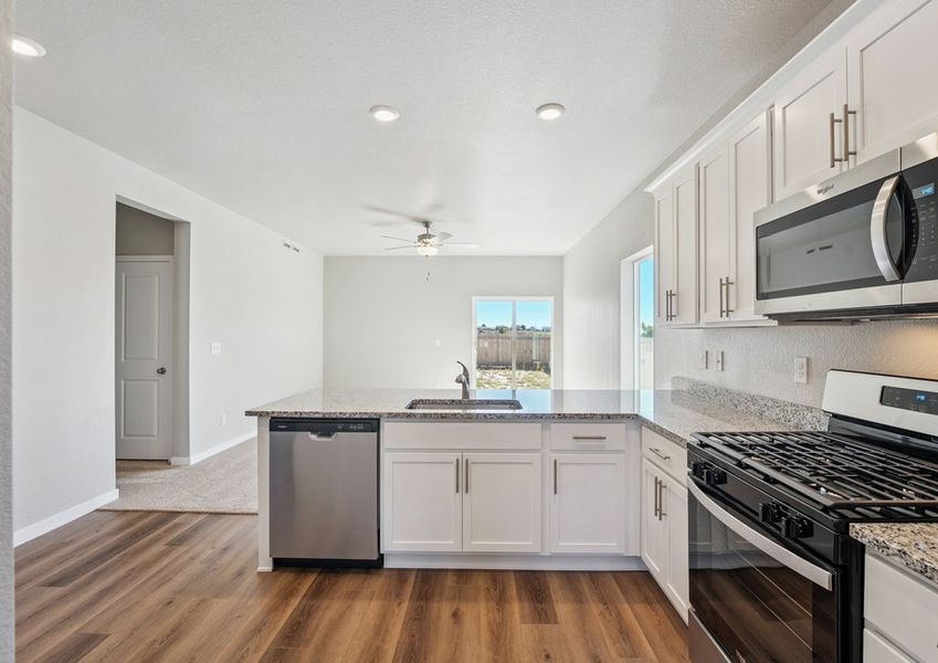 The kitchen has stainless steel appliances and plank flooring.