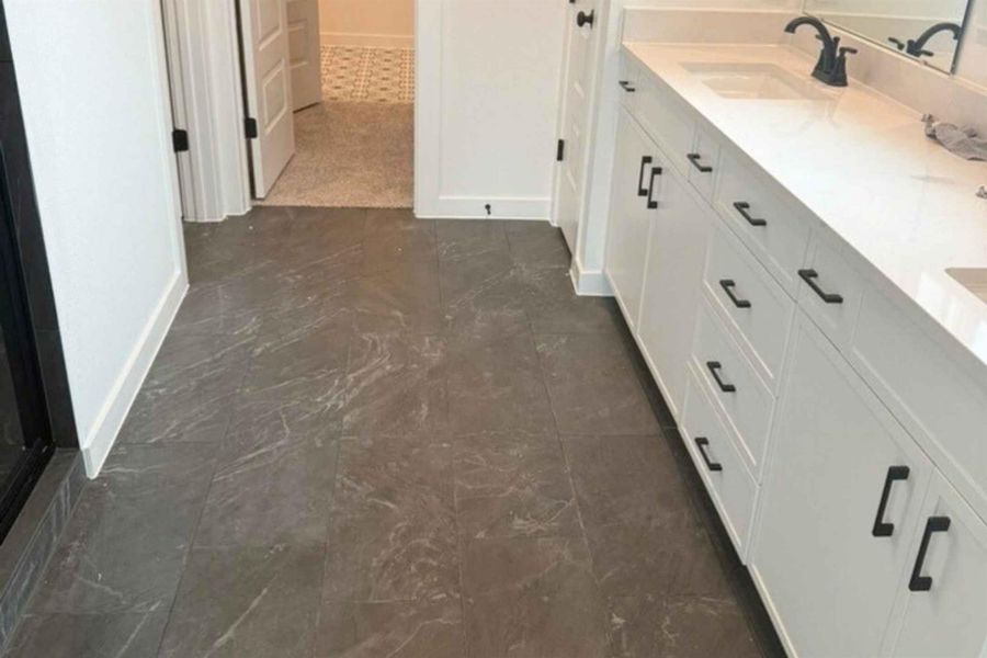 Full bathroom featuring double vanity and dark marble finish flooring