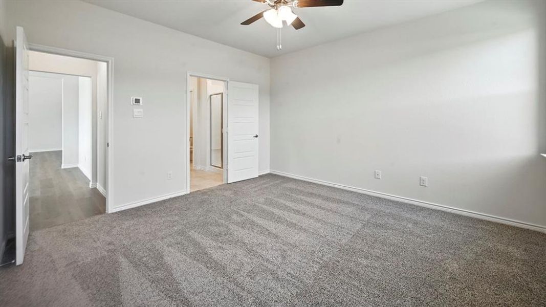 Unfurnished bedroom featuring carpet flooring, a ceiling fan, and ensuite bathroom