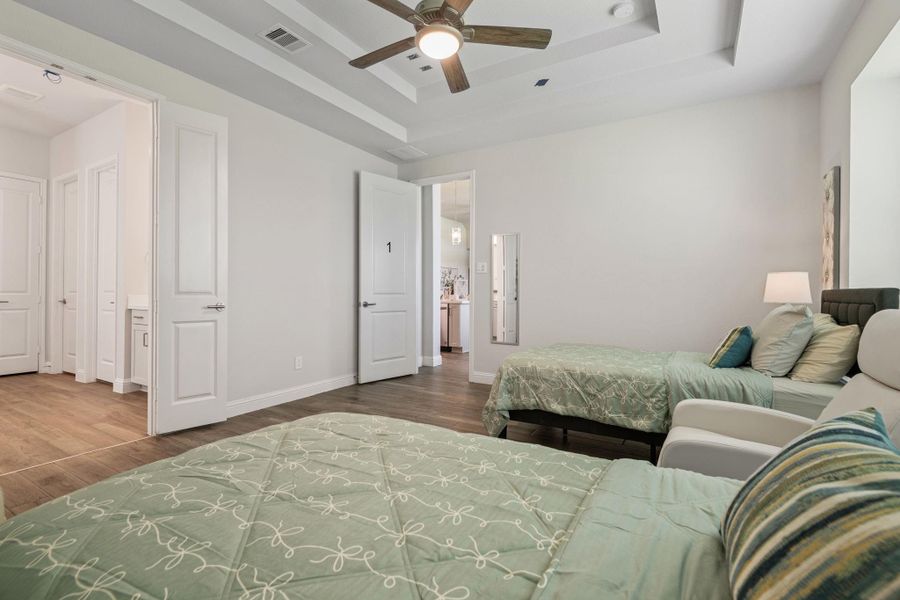 This spacious shared bedroom features two beds, neutral walls, and wood flooring. It includes a ceiling fan, ample natural light, and leads to a bathroom with double doors. The room has a cozy yet modern feel, perfect for relaxation. This spacious shared bedroom features two beds, neutral walls, and wood flooring. It includes a ceiling fan, ample natural light, and leads to a bathroom with double doors. The room has a cozy yet modern feel, perfect for relaxation.