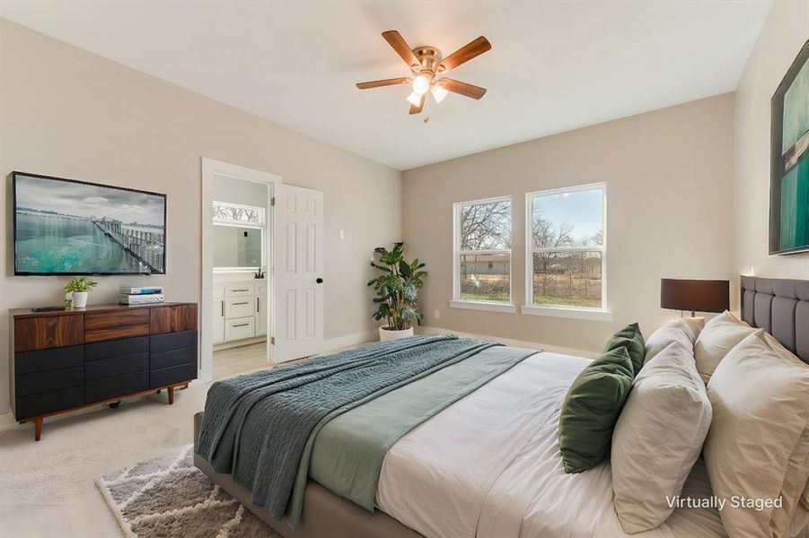 Bedroom with ensuite bath, light colored carpet, and ceiling fan