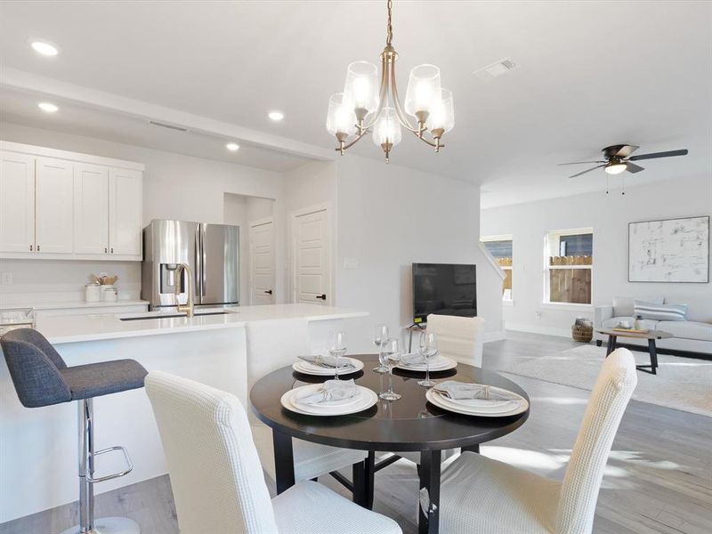 Dining area with ceiling fan with notable chandelier, sink, and light hardwood / wood-style flooring