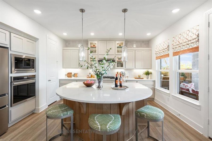 Kitchen featuring pendant lighting, light wood-style floors, recessed lighting, a kitchen breakfast bar, and stainless steel appliances