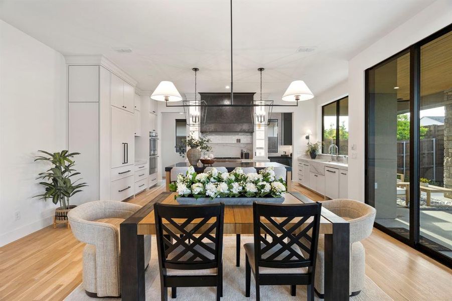 Kitchen with a center island, light wood finished floors, white cabinets, and decorative light fixtures Kitchen with a center island, light wood finished floors, white cabinets, and decorative light fixtures