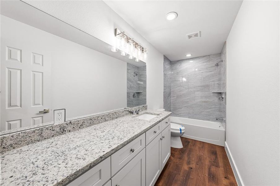 Bathroom featuring a double vanity with granite countertops, undermount sinks, and white shaker cabinetry