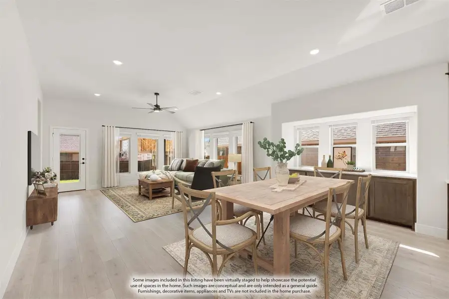 Open-concept dining and living area with wood dining table, light hardwood floors, and ceiling fan
