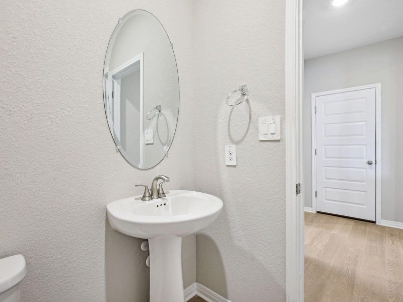 Bathroom with wood finished floors, toilet, a textured wall, and baseboards Bathroom with wood finished floors, toilet, a textured wall, and baseboards
