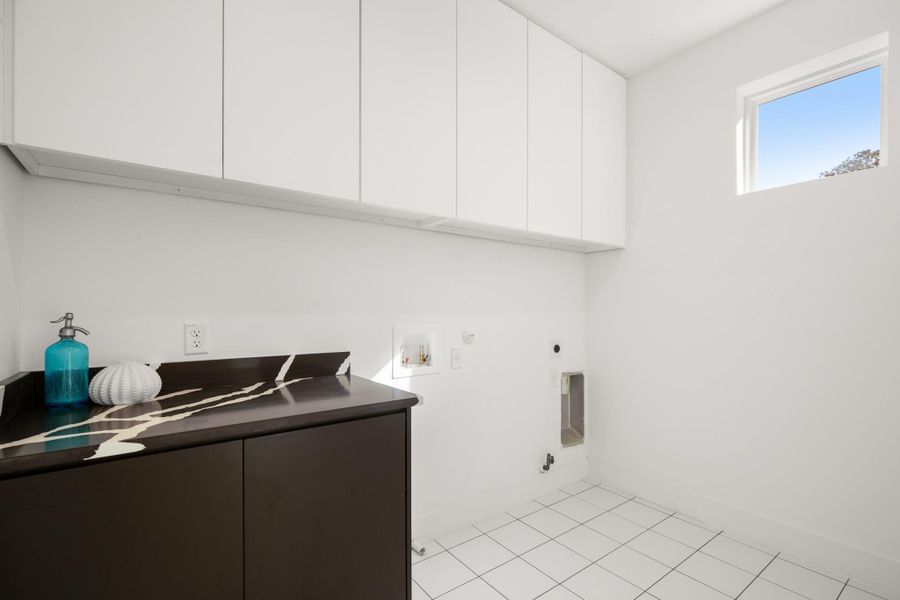 Laundry area on the second floor featuring gas dryer hookup, light tile patterned floors, washer hookup, hookup for an electric dryer, and cabinet space Laundry area on the second floor featuring gas dryer hookup, light tile patterned floors, washer hookup, hookup for an electric dryer, and cabinet space