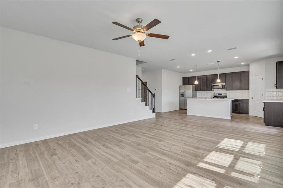 Unfurnished living room featuring light wood-type flooring and ceiling fan