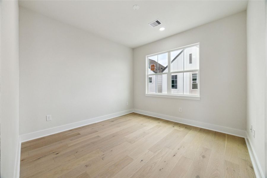 Bright and airy third-floor bedroom with a large window, offering a serene retreat.