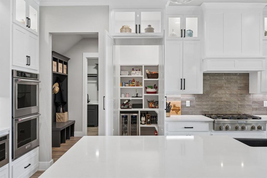 Kitchen with glass fronted cabinets, white cabinetry, stainless steel appliances, and wine cooler