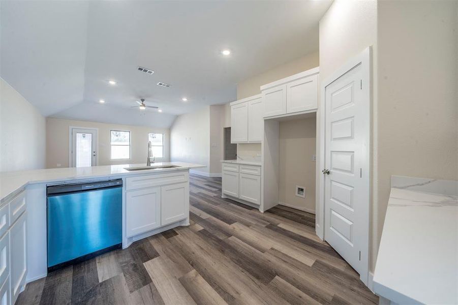 Kitchen featuring visible vents, white cabinets, dishwasher, dark wood-style floors, and a sink