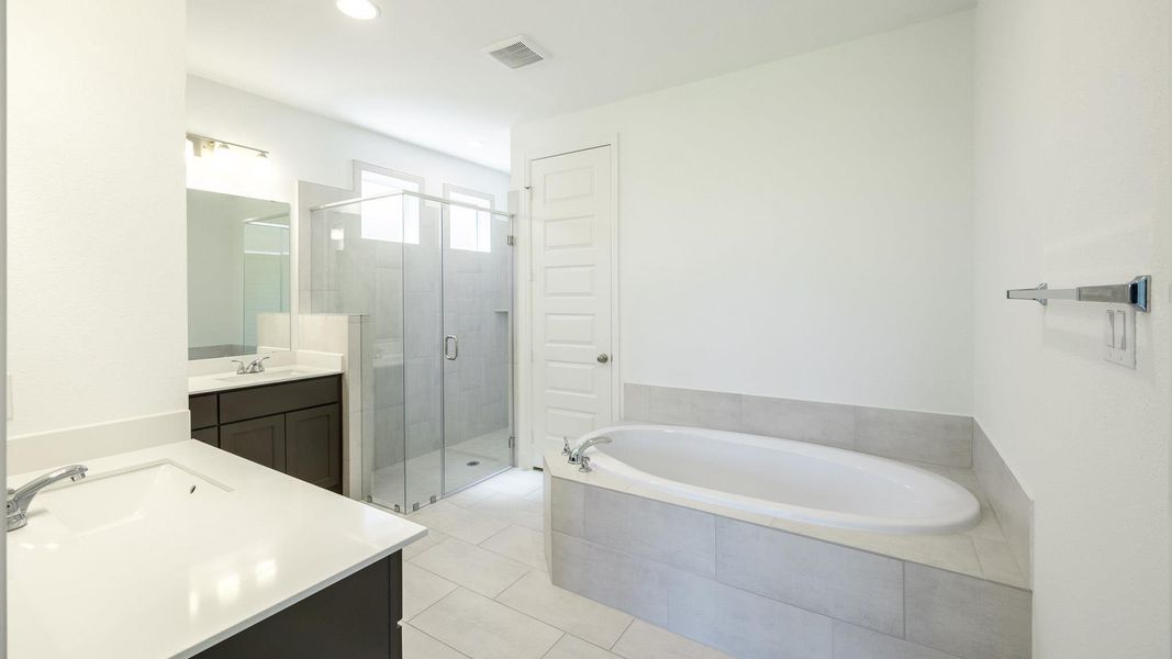 Bathroom with two vanities, a stall shower, a garden tub, light tile patterned floors, and recessed lighting Bathroom with two vanities, a stall shower, a garden tub, light tile patterned floors, and recessed lighting