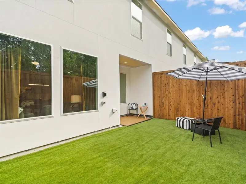 Back of property with fence, stucco siding, and a yard
