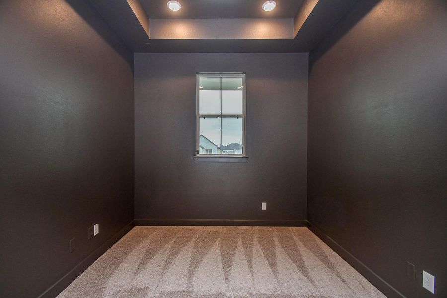 A dedicated home office or media room with a bold accent wall and recessed lighting.