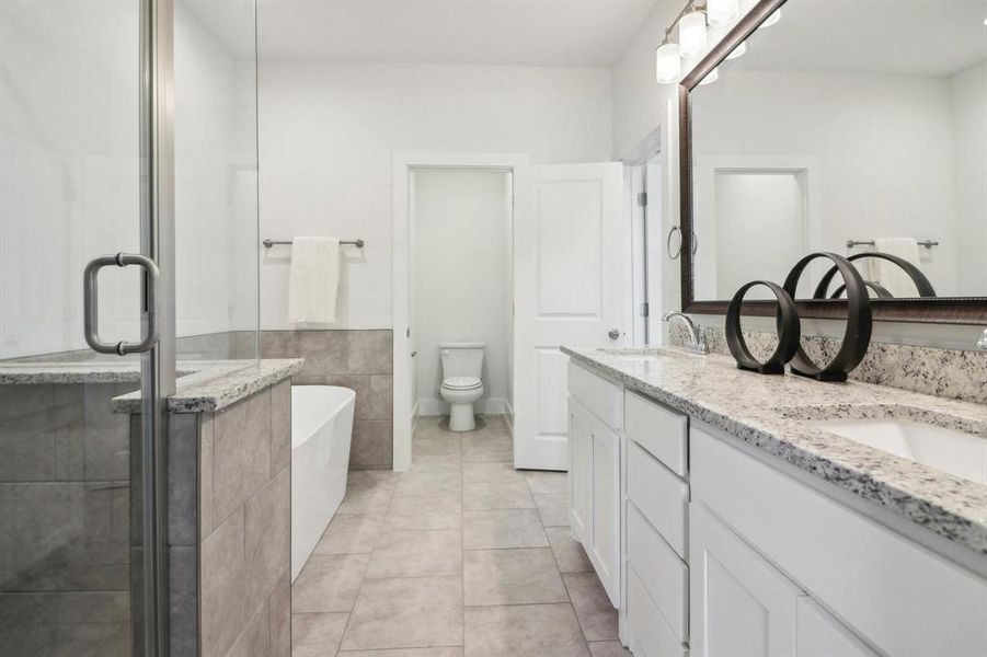 Full bathroom with tile patterned floors, separate shower and tub, vanity, and toilet