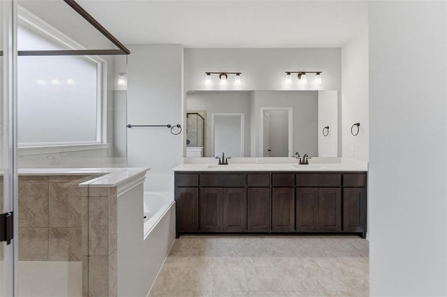Bathroom featuring a shower stall, double vanity, and a bath