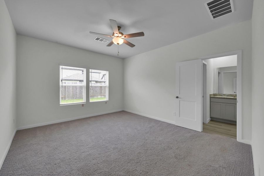 Spacious primary suite with natural light, plush carpeting, and a private ensuite bathroom. Spacious primary suite with natural light, plush carpeting, and a private ensuite bathroom.