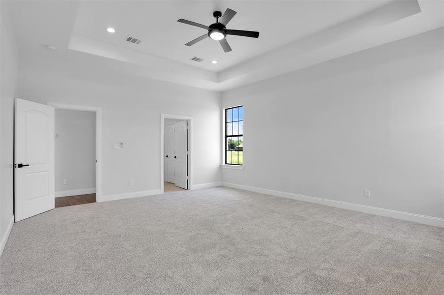 Unfurnished bedroom with light colored carpet and a tray ceiling