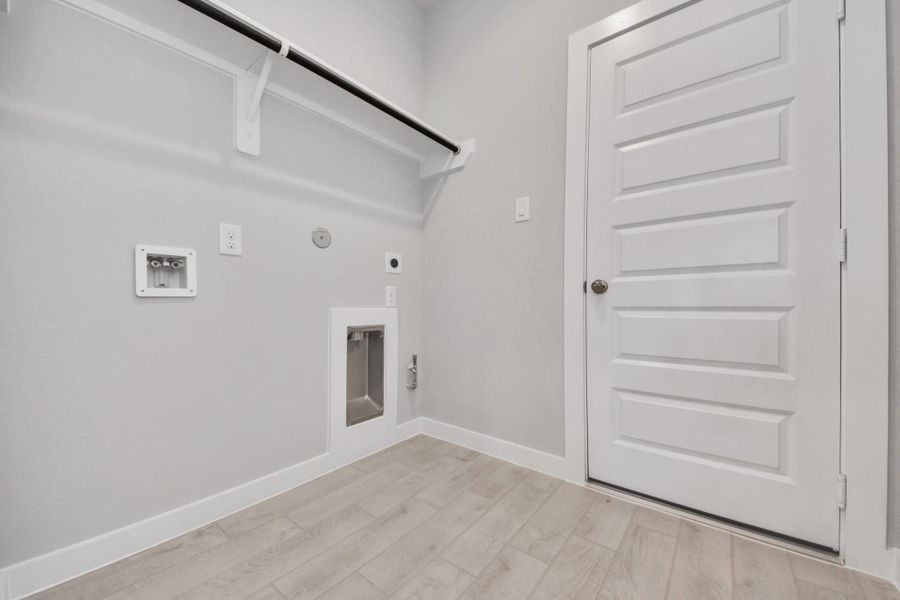 A perfect blend of functionality and comfort. Capture the essence of easy living with a first-floor laundry room, thoughtfully equipped with shelving for effortless organization. Both electric and gas connections available. Sample photo of completed home with similar floor plan. Actual colors and selections may vary.