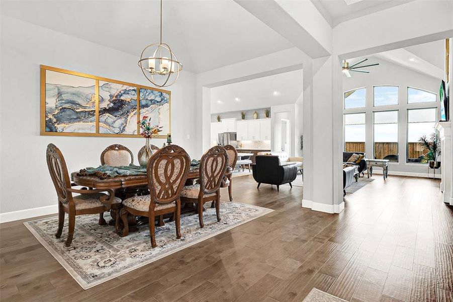 Dining space featuring a ceiling fan, wood finished floors, high vaulted ceiling, recessed lighting, and a chandelier