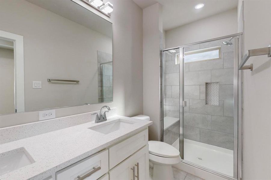 Bathroom featuring vanity, toilet, and a shower with door