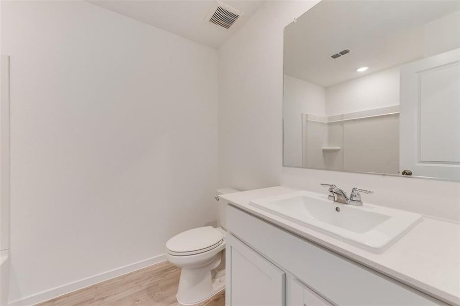 Bathroom with walk in shower, vanity, toilet, and hardwood / wood-style floors