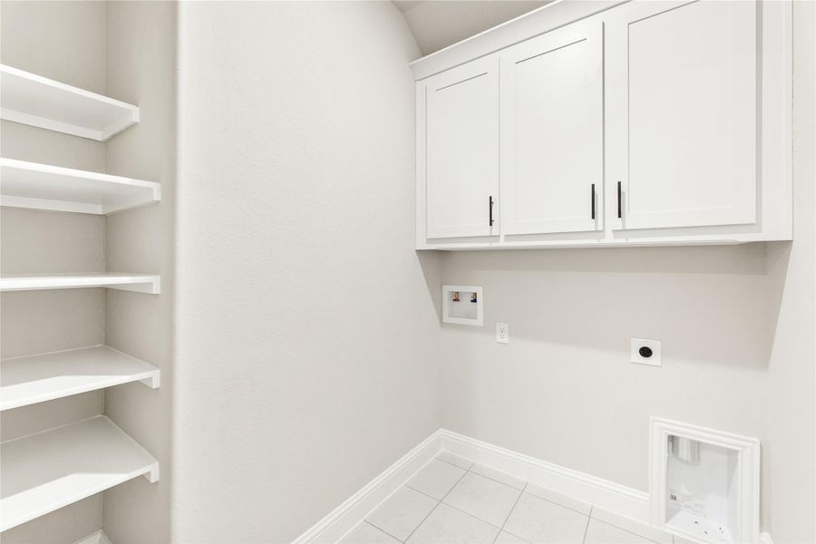 Laundry room with white upper cabinets, open shelving, washer hookups, and tile floor Laundry room with white upper cabinets, open shelving, washer hookups, and tile floor
