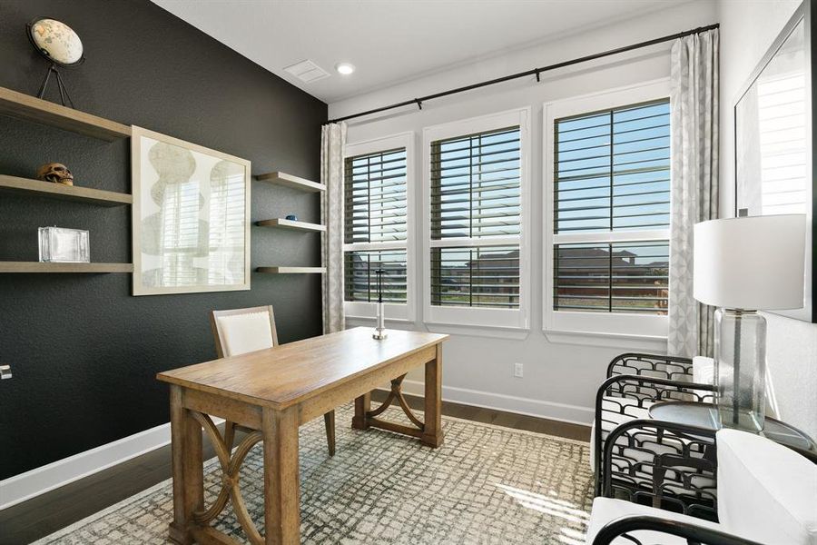 A dedicated home office with a wall of windows and a French door entrance.