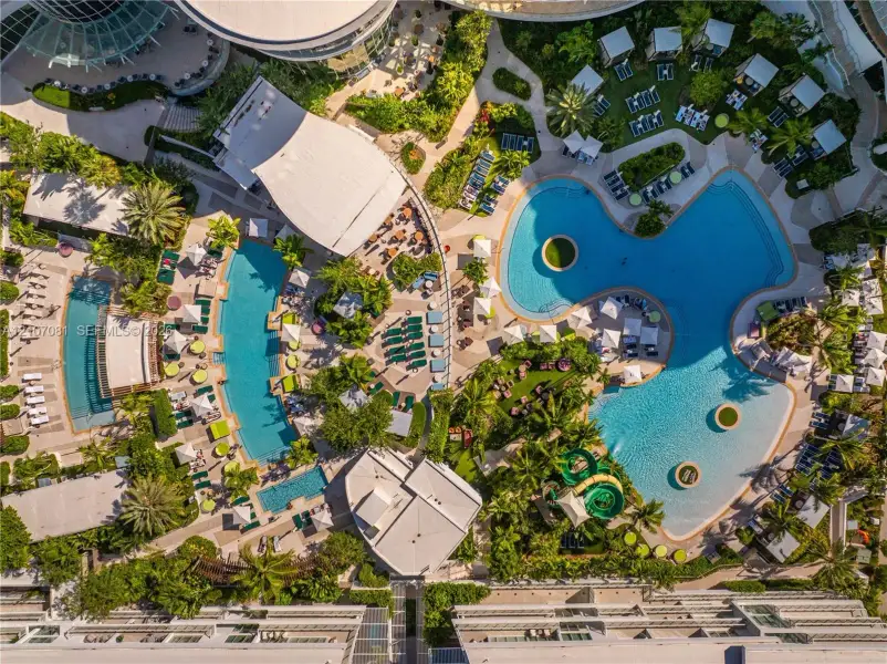 Expansive aquatic complex featuring multiple swimming pools, integrated water slide, paved patio surrounds, and mature landscaping Expansive aquatic complex featuring multiple swimming pools, integrated water slide, paved patio surrounds, and mature landscaping