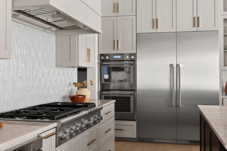 Masterfully appointed with double ovens and a bespoke tile backsplash that adds a subtle layer of texture
