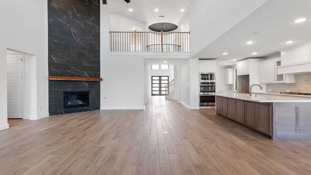 Kitchen with white cabinetry, a towering ceiling, appliances with stainless steel finishes, and light wood-type flooring