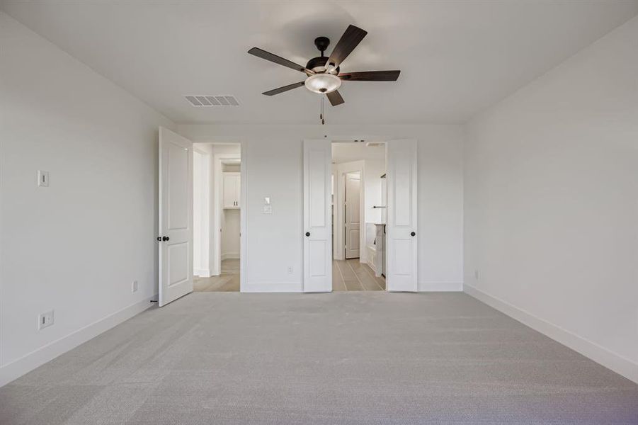 Unfurnished bedroom featuring light colored carpet, ceiling fan, and ensuite bath