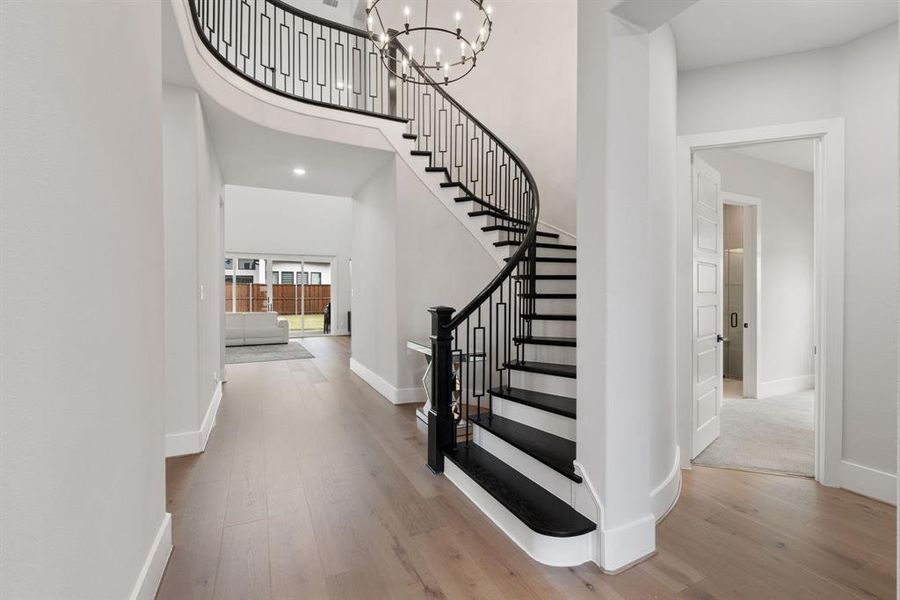 Foyer with a chandelier, wood finished floors, a towering ceiling, stairway, and recessed lighting
