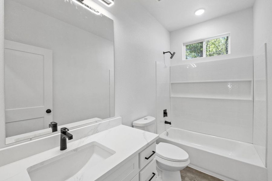 Modern white bathroom features clean lines, sleek fixtures, and a shower-tub combination. Modern white bathroom features clean lines, sleek fixtures, and a shower-tub combination.