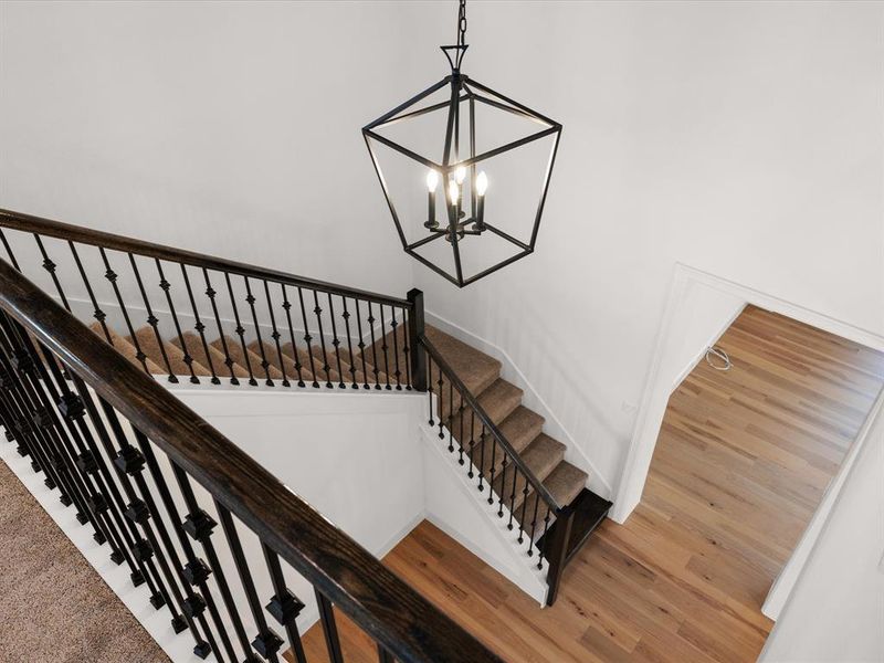 Stairs featuring wood finished floors and a chandelier