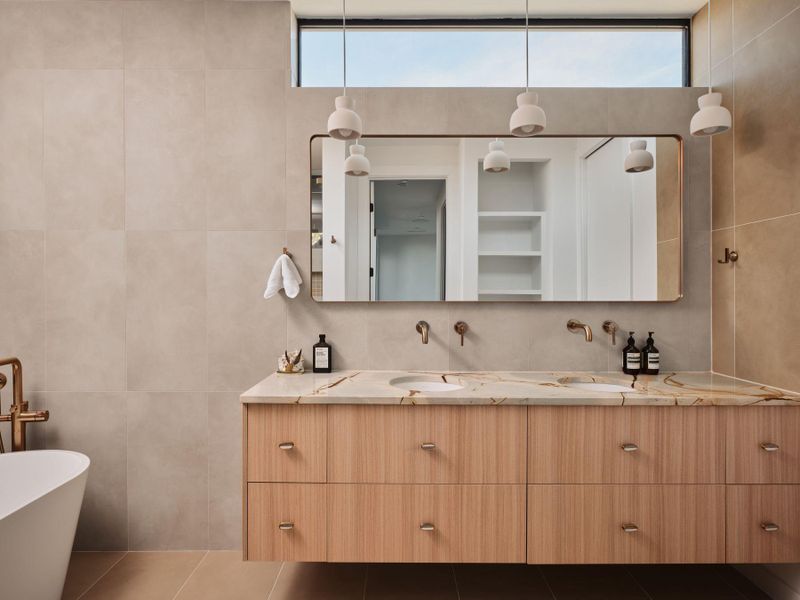 Bathroom with double vanity, tile walls, a freestanding bath, and tile patterned flooring