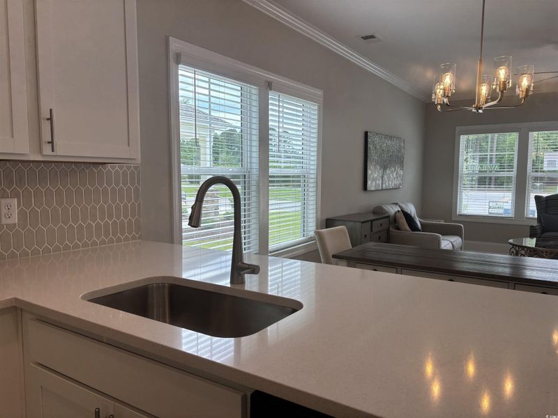 Kitchen with a sink, open floor plan, a chandelier, backsplash, and white cabinets