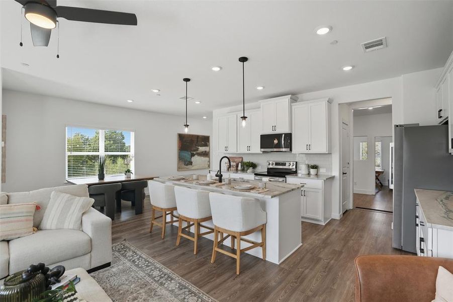 Kitchen featuring open floor plan, a breakfast bar area, dark wood-type flooring, white cabinetry, and recessed lighting Kitchen featuring open floor plan, a breakfast bar area, dark wood-type flooring, white cabinetry, and recessed lighting