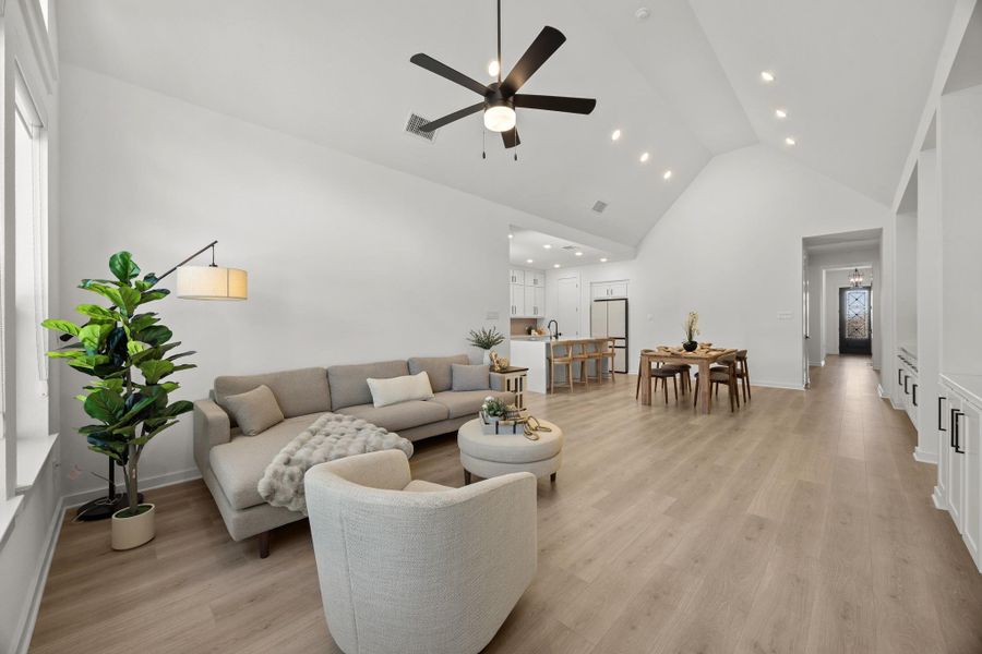 Living room featuring a ceiling fan, light wood-style flooring, vaulted ceiling, and recessed lighting