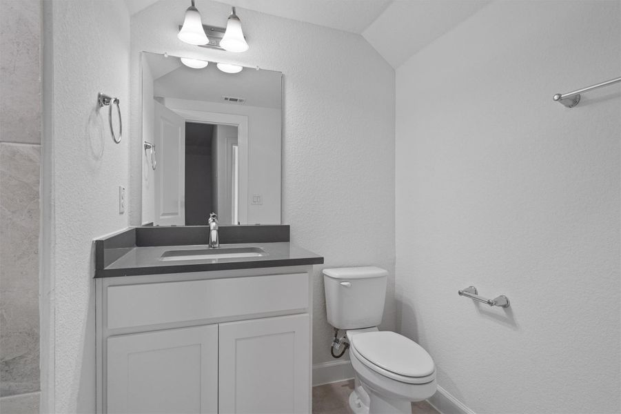 Modern bathroom featuring a white vanity with shaker-style cabinetry, dark countertop, and an undermount sink