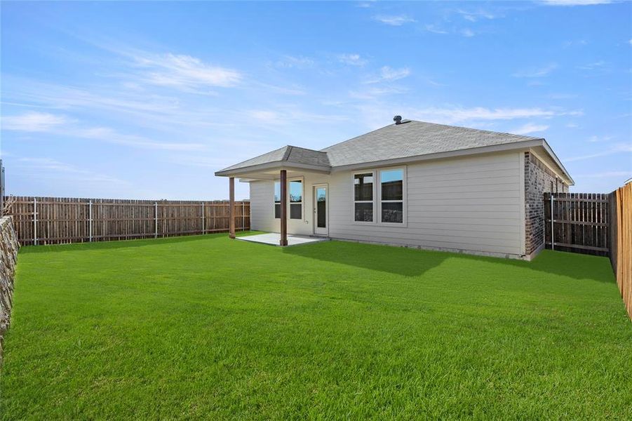 Back of house with a lawn and a patio