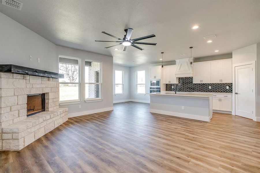 Unfurnished living room with light wood-style floors, a stone fireplace, ceiling fan, and recessed lighting